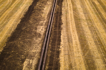 Open natural gas pipeline exposed that is under construction on agricultural field. Aerial view