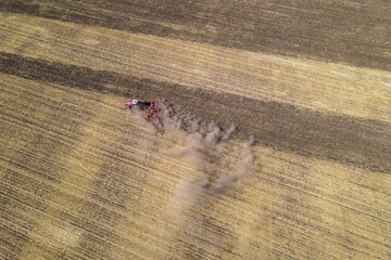 Tractor ploughing field at sunset, tracking aerial view