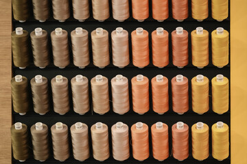Row of multi-colored thread spools in brown orange yellow tones
