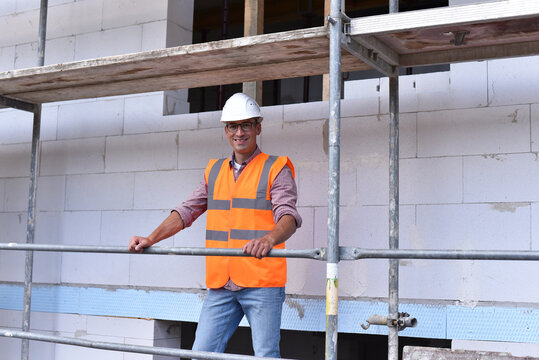 portrait smiling  construction manager / architect on site during the construction of a house - planning and control on site