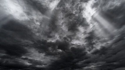 dark dramatic sky with black stormy clouds before rain or snow as abstract background, extreme weather, the sun shines through the clouds, high contrast photo