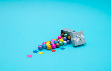 Gift box and colorful stars and balls on blue background. Party holiday concept. Copy space.