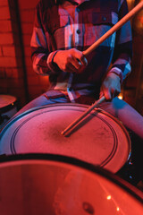 Crop anonymous male musician sitting at drummer set and performing song during live music show in...
