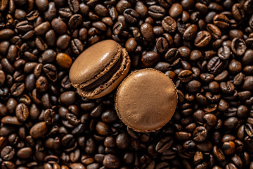 Sweet macaron dessert on coffee beans background. Top view.