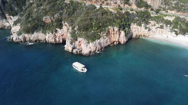 Aerial view of gorgeous Buyuk Chakil (black pebble) beach with emerald clear waters and boats, Kas, Turkey