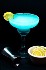 Margarita with tequila and lemons on black background.