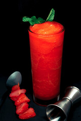 Vodka cocktail with strawberry and mint on a black background.