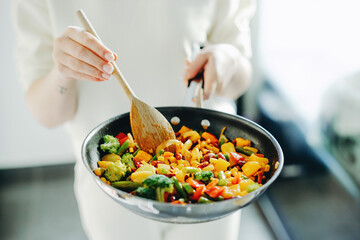 Woman cooking vegetables on pan