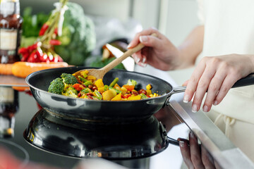 Woman cooking vegetables on pan