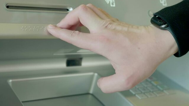 Withdrawal process. HDR. The hand of a blind person touches the special letters on the ATM for information.