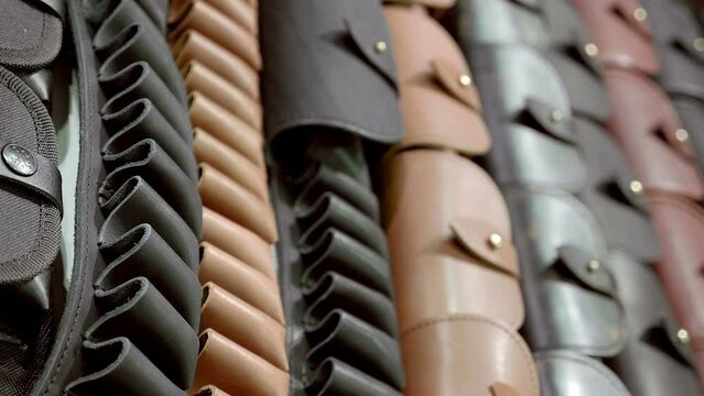 Large selection of waist bandolier made of genuine leather in a hunting shop. Closeup. Macro. Follow focus