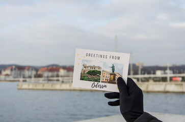 Pier in Sopot, a woman's hand in a black glove holds a postcard with the inscription in English 