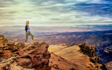 Fototapeta premium Woman on a rock enjoying the panorama of the Sierra Nevada mountain range in Spain.