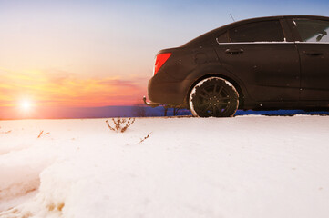 Close-up of a car on a winter road against a sky with a sunset - 544198611