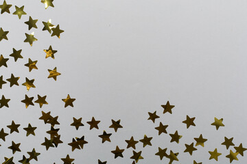 Golden confetti stars on color background, top view