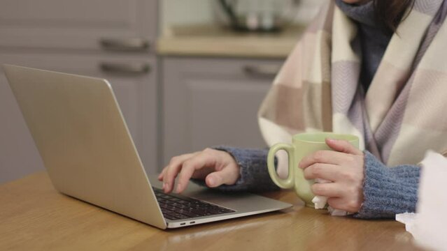 Unrecognizable woman wrapped warm blanket laptop sit at kitchen table cold indoors turn off heat economy problems gas supply central heating problems economy crisis cost of living in Europe bankruptcy