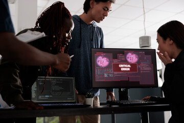 Team of software developers looking at monitor dealing with security breach alert on pc, trying to solve hacking and critical error. Engineers using terminal window and having system hacked crash.