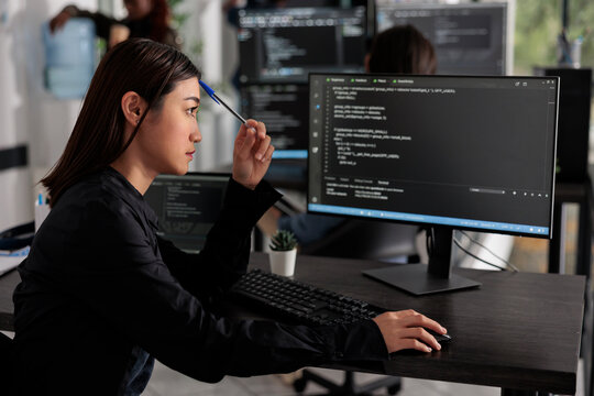 Pensive programmer thinking at ideas trying to write code and create new interface in data room. Web developer programming server database in busy artificial intelligence developing agency.