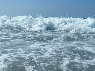 Beautiful sea with waves splashing warm sparkling clear blue water in a warm tropical oriental country southern resort. Background, texture