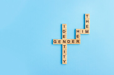 Words Gender Identity and His, Her and Them made up of wooden blocks with letters on blue...