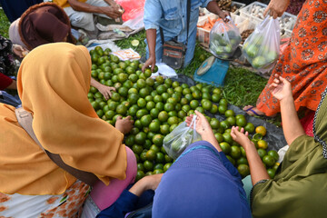 women are crowding to buy cheap local oranges at a traditional market, Indonesia.