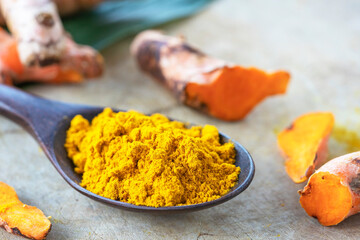 Turmeric powder in black wooden spoon.
