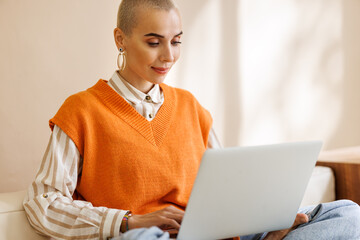 Beautiful woman freelancer with very short hair   working at laptop at home