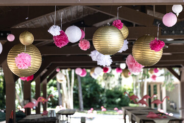 hanging gold and pink paper lanterns at a local park for a birthday party celebration