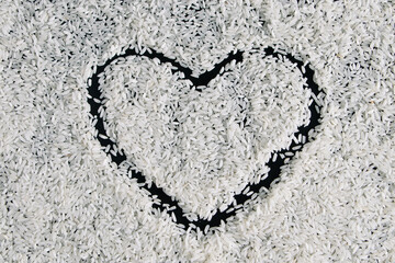 Heart-shaped rice on dark background. Love and valentines day concept. Raw long white rice in shape of heart. Traditional Asian food.