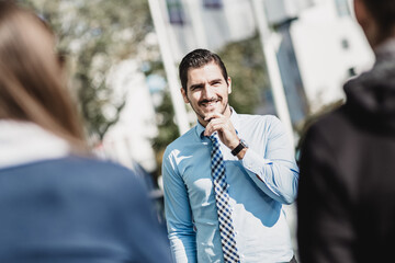 Attractive young businessman with a friendly smile having informal out of office meeting on a suny day.