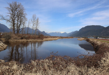Autumn landscape in a sunny day with mountains and calm pond