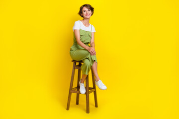 Full body length photo of adorable businesswoman sitting bar chair relax after hard working days weekend isolated on yellow color background