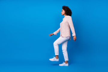 Full length photo of sweet adorable girl dressed pink blouse walking up empty space isolated blue...