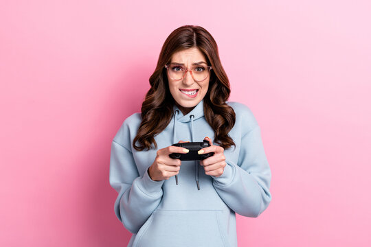 Portrait of gamer girl arms hold controller plat games biting lips tryhard isolated on pink color background