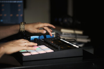 man's hands playing on a beats machine in a home recording studio