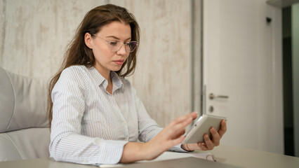 One woman female caucasian entrepreneur businesswoman or secretary sitting at her office at desk work on digital tablet use for online search wear shirt copy space