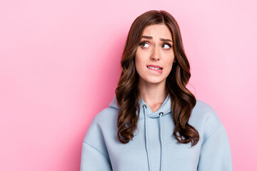 Photo of doubtful unsure girl dressed grey sweatshirt biting lip looking empty space isolated pink color background - obrazy, fototapety, plakaty