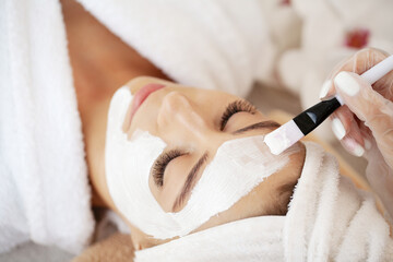Beautiful woman with facial mask at beauty salon