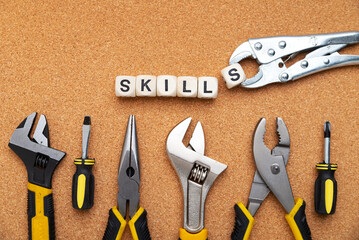 SKILLS word written on wood blocks. Various tools on cork background. business concept.