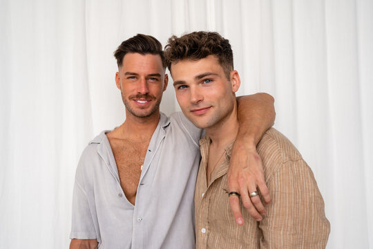 Gay couple smiling with white curtain background