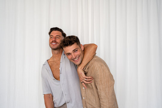 Beautiful Gay couple arm around shoulder and happy with white curtain background