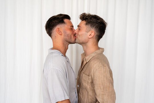 Beautiful Gay couple kissing and laughing with white curtain background