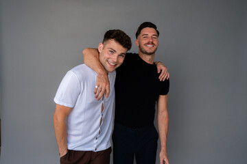 beautiful gay couple smiling and arms around shoulders looking at camera