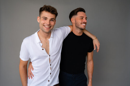 beautiful gay couple smiling and arms around shoulders and happy