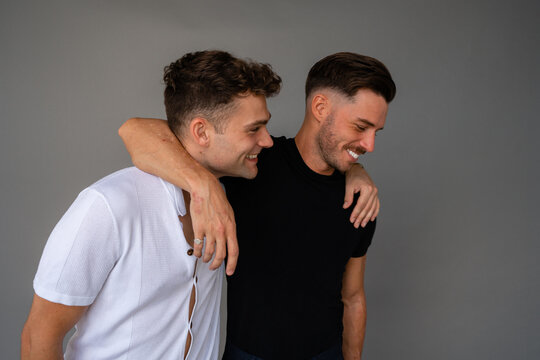 beautiful gay couple smiling and arms around shoulders looking at eachother