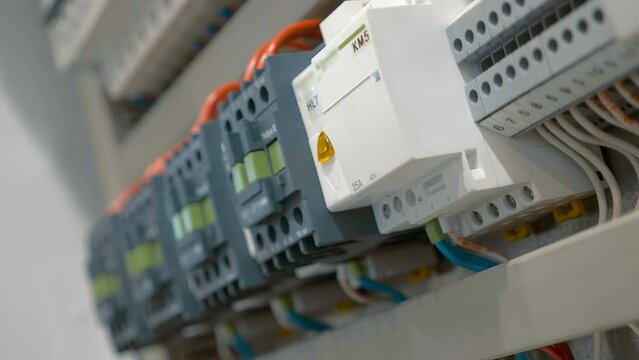 Electrical box with many wires, rows of switches, electrical parts, automatic breakers. Closeup. Follow focus