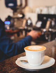 View of barista working at coffee machine in coffee house bar, bartender barman making cappuccino or latte, bartender preparing coffee drink at the cafe counter