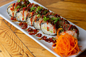 Asian sushi roll with toppings and vegetables. Filled with crab, avocado, cucumber and sauce.