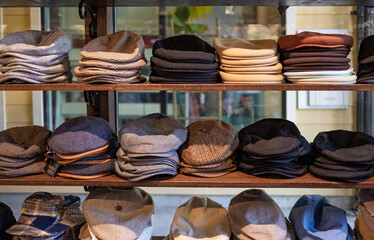 Varieties of caps and hats for men on the shelf of a clothing shop. Peaky blinders style hats....