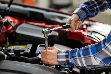 Female auto mechanic unscrewing a nut to replace a car spark plug.